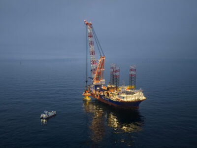 Van Oord installation vessel installing a monopile at sea at dusk