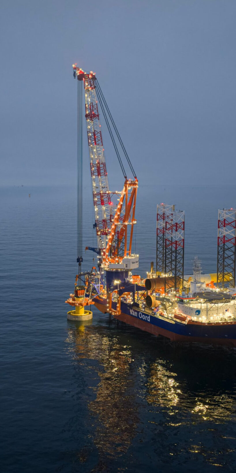 Van Oord installation vessel installing a monopile at sea at dusk